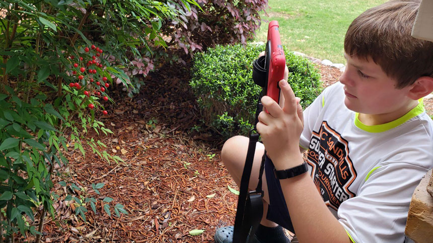 Tay Tranel, a sixth grade student at St. John Paul II Catholic School, photographs a photo of berries near his home to upload to the school's National Geographic BioBlitz.