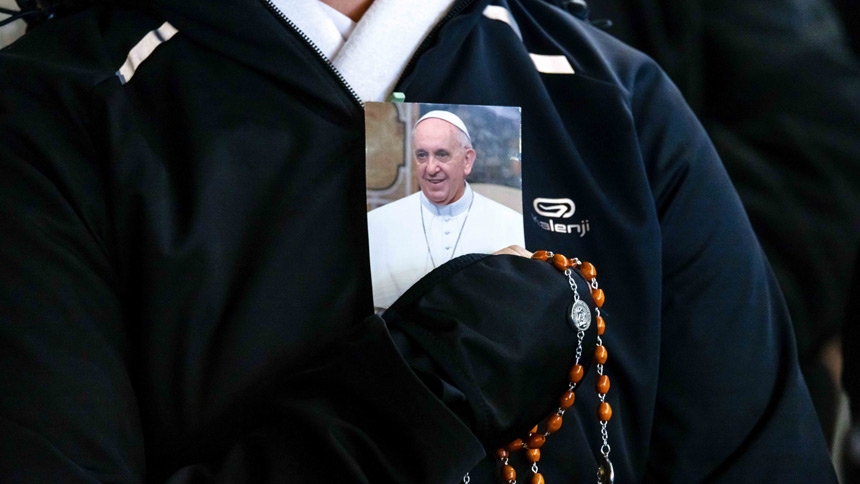 A person holds a rosary and a photo of Pope Francis as people gather in St. Peter’s Square at the Vatican to recite the rosary for Pope Francis with Cardinal Robert F. Prevost, prefect of the Dicastery for Bishops, March 3, 2025. (CNS photo/Pablo Esparza)