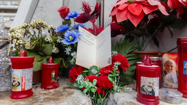 A get-well card for Pope Francis is set among flowers and votive candles at the base of a statue of St. John Paul II outside Rome's Gemelli hospital Feb. 18, 2025. (CNS photo/Pablo Esparza)